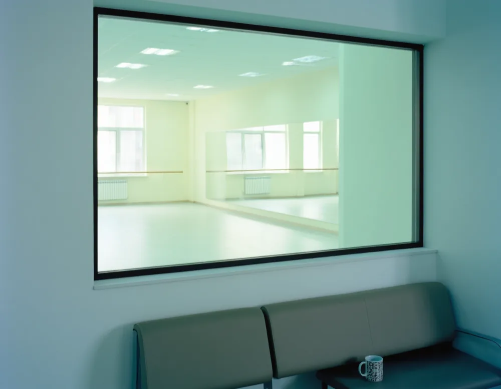 Two adults seen from behind watching a class through the glass window of the waiting area